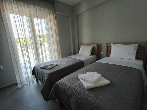 two beds sitting in a room with a window at Irina's Apartment 6 in Psakoudia