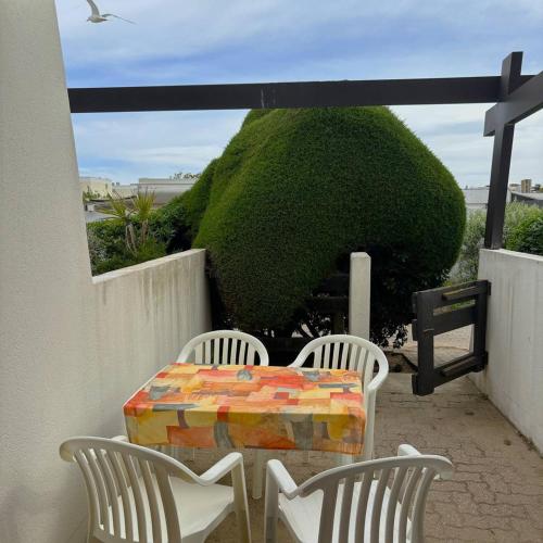 une table et quatre chaises sur une terrasse avec un buisson dans l'établissement Studio Port Nature PN24 - 2 personnes, au Cap d'Agde