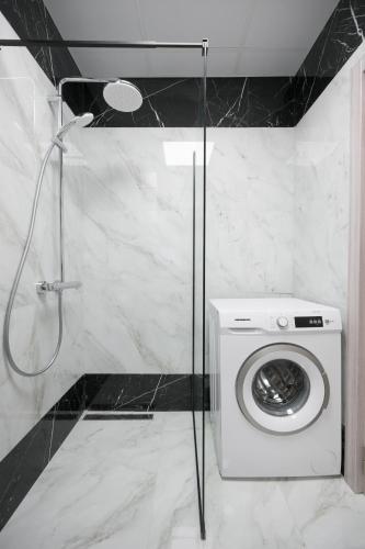 a washing machine in a bathroom with a shower at Azur Properties ap51 in Shkorpilovtsi