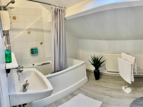 ein weißes Badezimmer mit Badewanne und Waschbecken in der Unterkunft Cosy Loft Apartment with Sea Views Above Village Pub The Stag Inn Crosby Maryport in Crosby