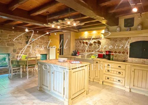 - une cuisine avec des placards en bois et un mur en pierre dans l'établissement Le Moulin de Kerhonn, à Pommerit-le-Vicomte