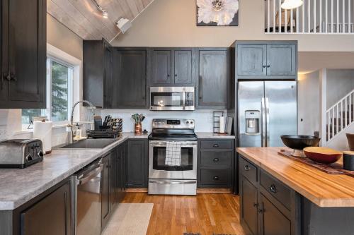 a kitchen with gray cabinets and stainless steel appliances at Serenity Shores 5BD Hot Tub Fishing Hiking in Traverse City