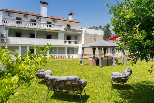 a yard with chairs and an umbrella and a building at Calejo House – Pool & Sports & Grill Retreat in Nogueira