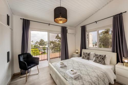 ein Schlafzimmer mit einem Bett und einem Stuhl und Fenstern in der Unterkunft Larnaca Seaside Villa Marina 44 in Perivolia
