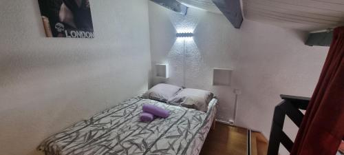 - une petite chambre avec un lit et des oreillers violets dans l'établissement Résidence Front de Mer, Appt 5 couchages, au Barcarès
