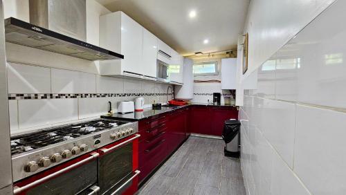 La cuisine est équipée de placards rouges et d'un four avec plaques de cuisson. dans l'établissement Maison de Vacances mais pas de fêtes, à Stains