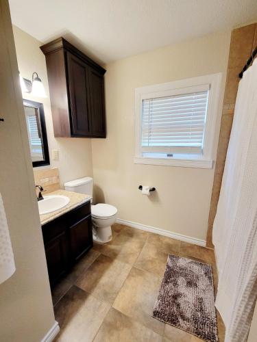 a bathroom with a toilet and a sink and a window at Craftsman by Downtown Uvalde in Uvalde