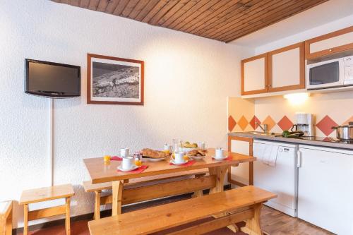 cocina con mesa de madera, mesa y barra en Résidence Pierre & Vacances Le Schuss en Val Thorens