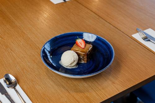 a blue plate with a piece of cake and ice cream at Holiday Inn Express Aberdeen Airport by IHG in Dyce