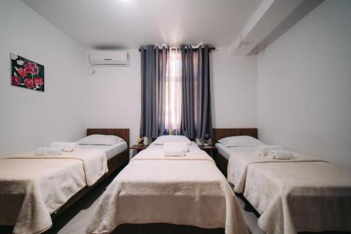 a group of three beds in a room at Hotel Skrapari in Çorovodë
