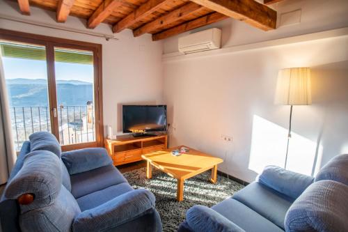 a living room with two blue couches and a television at Casa Rural Vistes de Morella in Morella