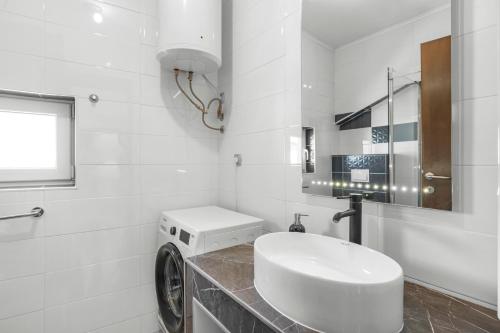 a white bathroom with a washing machine and a sink at Apartments 2 with pool and private jacuzzi in Vodice