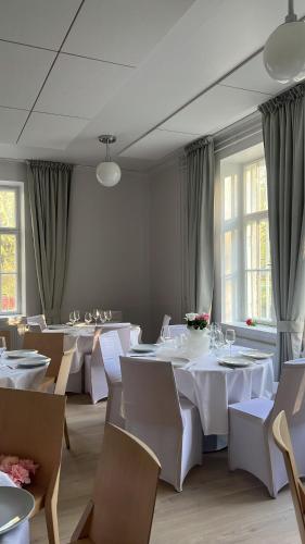 a dining room with white tables and chairs and windows at Kuopion Kesäranta in Kuopio
