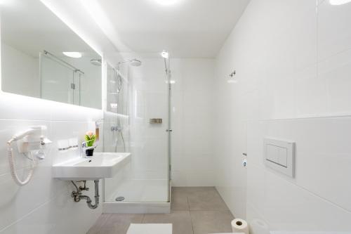 a white bathroom with a sink and a shower at Vienna Stay Apartments Schönbrunn in Vienna