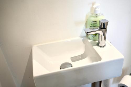 a white sink with a bottle of soap on it at Appartement de charme in Vaux-sur-Sûre