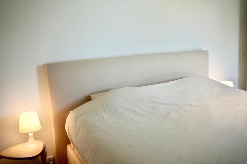 a bedroom with a white bed and a lamp at Appartement de charme in Vaux-sur-Sûre