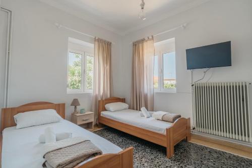 a bedroom with two beds and a flat screen tv at Theofania's Home in Kiáton