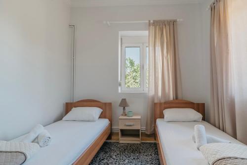 two beds in a room with a window at Theofania's Home in Kiáton