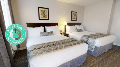 two beds in a hotel room with a green sign at Dilworth Inn Kelowna in Kelowna
