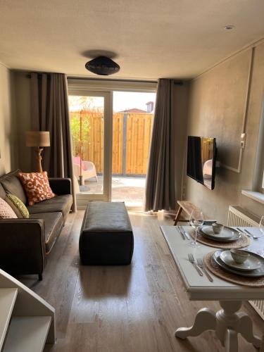 a living room with a couch and a table at Beachhouse Noteboom, omheinde tuin in Noordwijk aan Zee