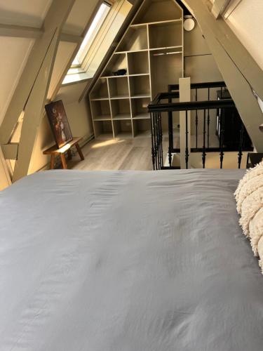 a attic room with a bed and a staircase at Beachhouse Noteboom, omheinde tuin in Noordwijk aan Zee