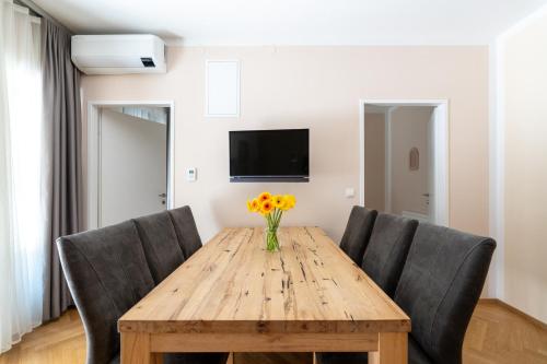 a wooden table with chairs and a vase of flowers on it at Vienna Stay Apartments Schönbrunn in Vienna
