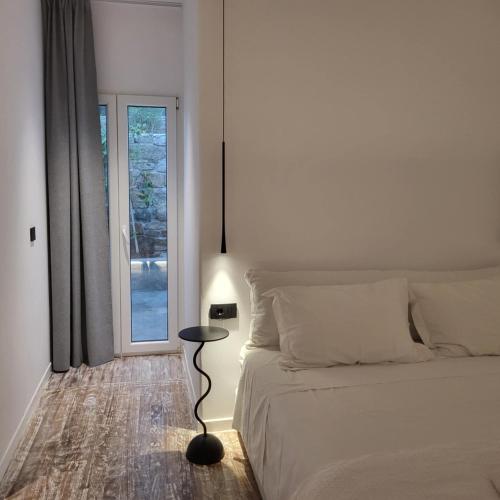 a bedroom with a bed and a table next to a window at Oro suites budget in Mikonos