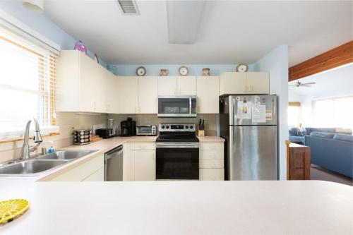 a kitchen with white cabinets and a stainless steel refrigerator at Private Pool Spa & Spacious Deck in Corolla