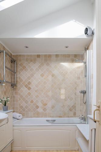 a bathroom with a tub and a shower at Storehouse Cottage in Penrhyn Bay