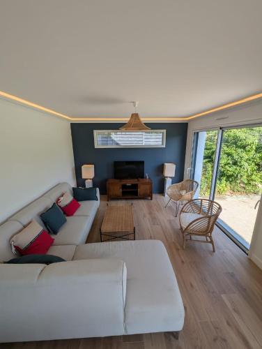 un salon avec un canapé et une télévision dans l'établissement Maison familiale design proche plage draps fournis, à Étel