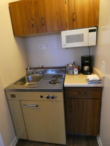 a kitchen with a sink and a stove and a microwave at Dilworth Inn Kelowna in Kelowna