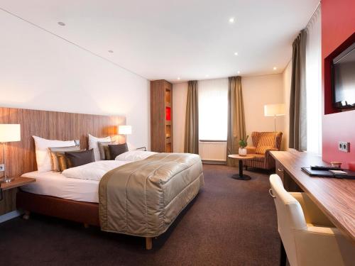 ein Hotelzimmer mit einem großen Bett und einem Schreibtisch in der Unterkunft Valuas in Venlo