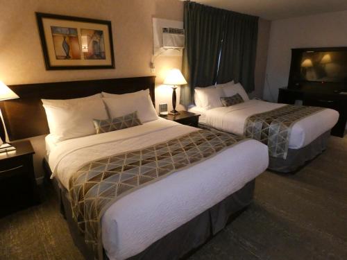 a hotel room with two beds and a television at Dilworth Inn Kelowna in Kelowna