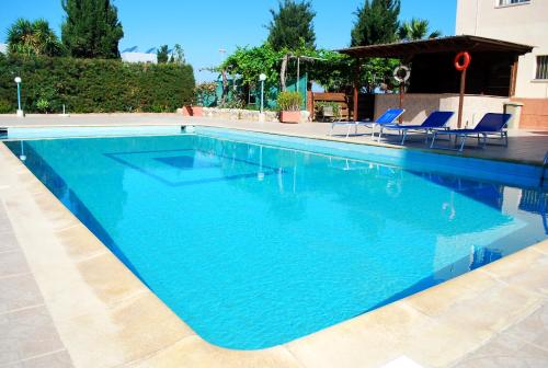 a large blue swimming pool with blue chairs in it at Georgia Apartments in Paphos City