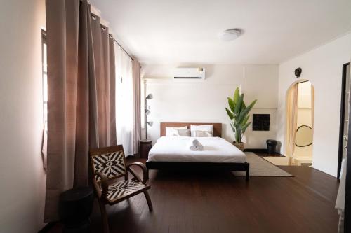 een slaapkamer met een bed en een stoel bij Rwanda Naziza - Private Villa in the Old Town City - PRIME LOCATION I Daily Housekeeping in Chiang Mai