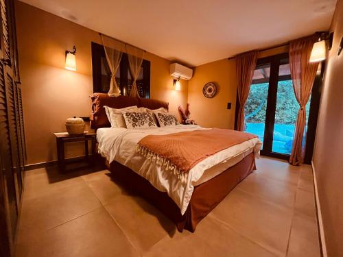 a bedroom with a large bed and a large window at Garden villa two-bedroom suite in Vari