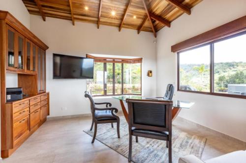 a living room with a table and chairs and a television at Casa de Lujo con Piscina y Vistas Panorámicas Oro Monte, Naranjo in Naranjo