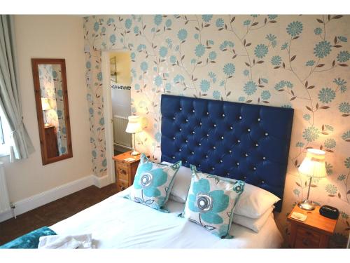 a bedroom with a bed with a blue headboard at Ashlea Guest House in Banbury