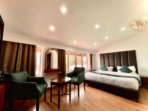 una camera da letto con un letto, due sedie e un tavolo di Hotel Roshie Mall Road Mussoorie Near Picture Palace a Mussoorie