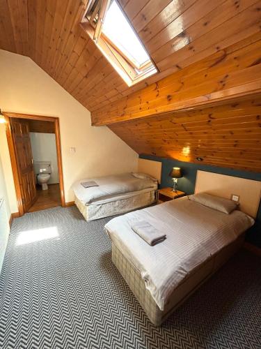 two beds in a room with a wooden ceiling at The Egerton Arms Hotel Salford in Manchester