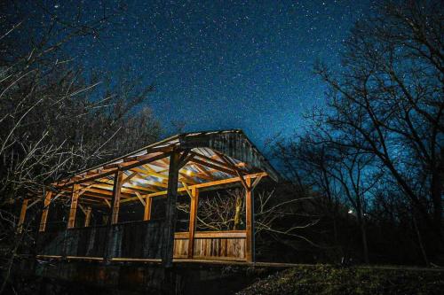 a wooden building with lights on it at night at Covered Bridge Tiny Home Bus On The Water In Rrg in Stanton