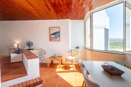 a living room with a table and chairs and windows at Muito acolhedor com vista de mar in Colares