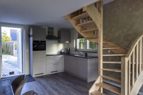 a kitchen with a staircase leading up to a kitchen with white cabinets at Boszicht aan Zee, new holiday home in Biggekerke in Biggekerke
