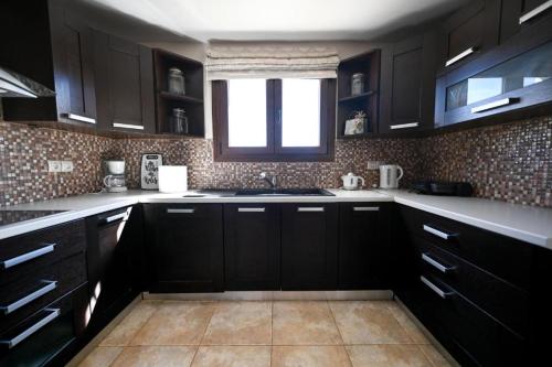 a kitchen with black cabinets and a window at Villa Theadora in Skiathos