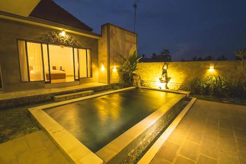 a swimming pool in front of a house at night at Ubud Lestari Villa in Ubud