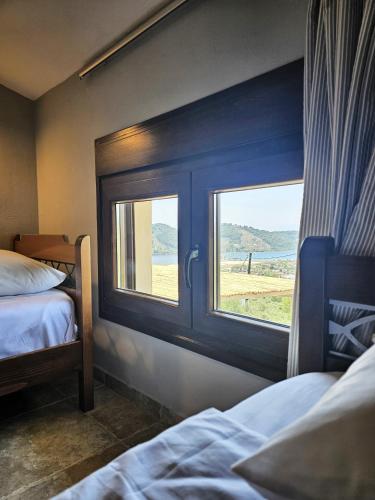 a bedroom with two beds and two windows at Villa Theadora in Skiathos