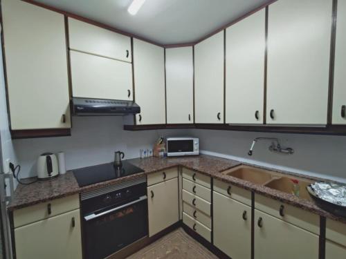 eine Küche mit weißen Schränken und einer Spüle in der Unterkunft Beachfront apartment in Sant Salvador