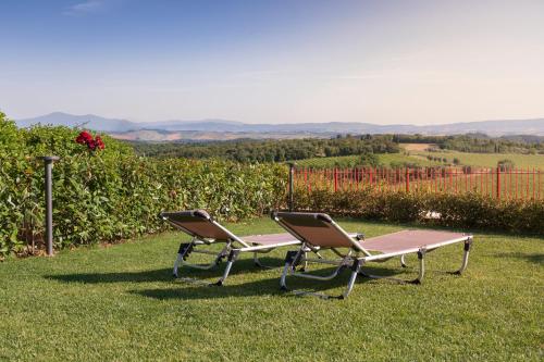 two chairs and a picnic table in the grass at Casa Nataly Chianti - Jeky Stay in Castelnuovo Berardenga