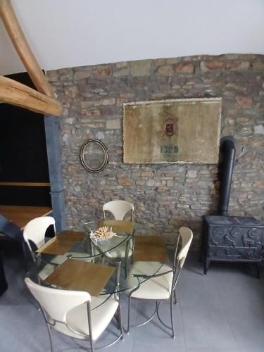 a dining room with a table and chairs and a stove at Le charme des Pierres et wellness in Ohey