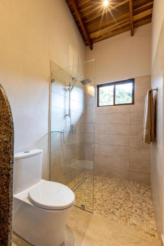 a bathroom with a toilet and a glass shower at Casa de Lujo con Piscina y Vistas Panorámicas Oro Monte, Naranjo in Naranjo